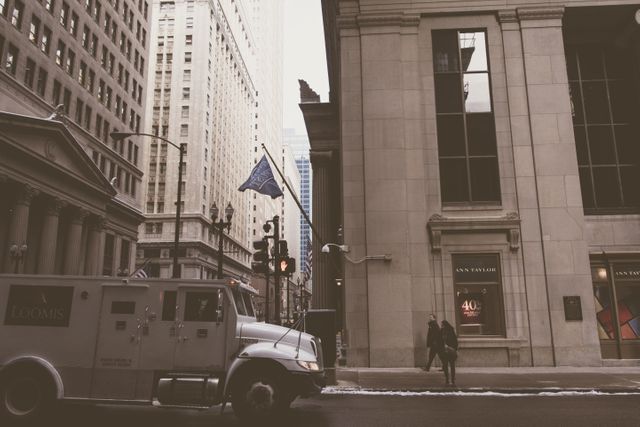 Downtown city street scene on a cold winter day with an armored car parked near buildings. Captures urban life and architecture. Could be used for business, finance, or urban lifestyle contexts.