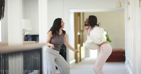Diverse friends dancing in bright home hallway having fun wearing casual loungewear