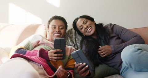 Smiling Women Relaxing with Smartphones at Home