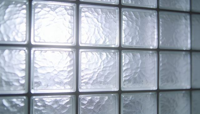 Textured glass block wall transmitting diffused backlight for privacy and modern interiors