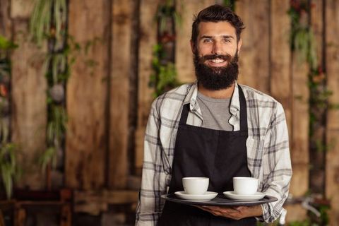 Bearded Barista Serving Coffee in Rustic Cafe Environment