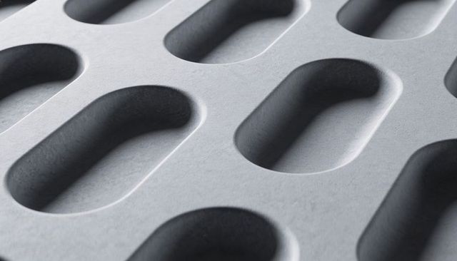 Gray molded panel featuring repeating oval recesses closeup textured industrial pattern