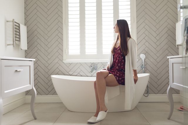 Thoughtful Woman Sitting on Bathtub in Modern Bathroom - Download Free Stock Photos Pikwizard.com