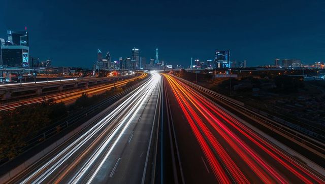 Futuristic light trails over major highway at night with urban skyline