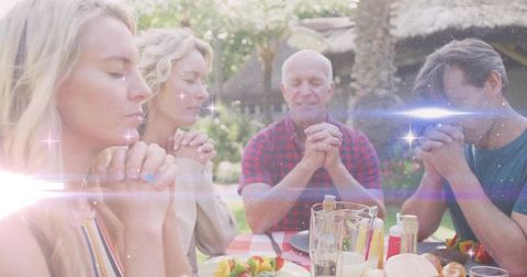 Family Praying at Outdoor Table in Rustic Garden Setting