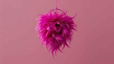 Vibrant magenta dreamcatcher feathered ornament swaying against pink background