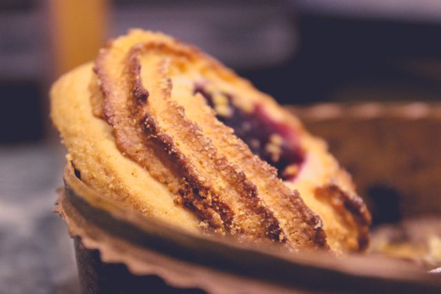 Close-up view of a freshly baked pastry featuring a blueberry-filled swirl. This high-quality image is perfect for food blogs, recipes, bakery advertisements, or dessert menu visuals. Its rich colors and textures make it suitable for promoting culinary content, restaurant flyers, or social media food posts.