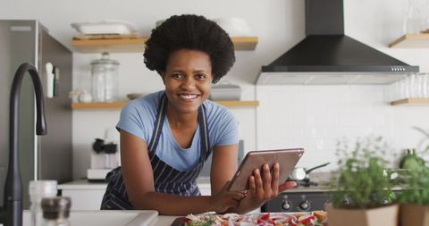 Cheerful Woman Cooking with Tablet in Bright Modern Kitchen