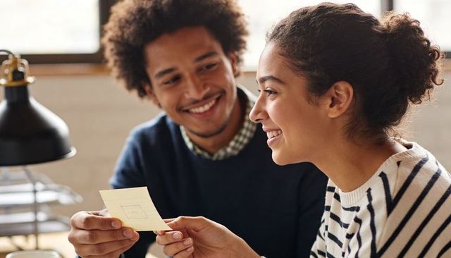Young couple collaborating over sketch note in cozy sunlit workspace
