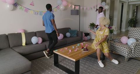 Decorating pastel baby shower with friends at home, pregnant woman in yellow dress