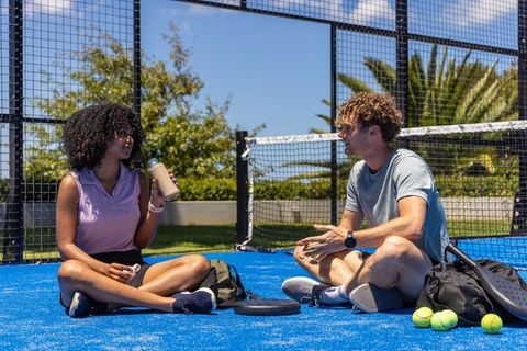Resting and chatting on blue pickleball court with paddles and reusable bottle