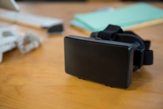 Virtual reality headset resting on an office desk, representing modern technology and innovation in the workplace. Ideal for use in articles or advertisements about VR technology, office gadgets, or digital transformation in business environments.