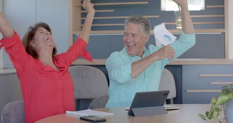 Senior Couple Joyfully Celebrating While Discussions on Gadget