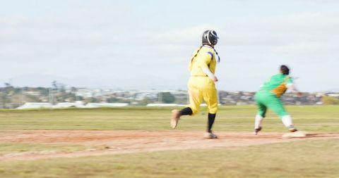 Female athletes sprinting on softball field near base