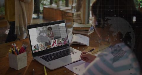 Child attending virtual class on laptop taking notes at home remote learning concept