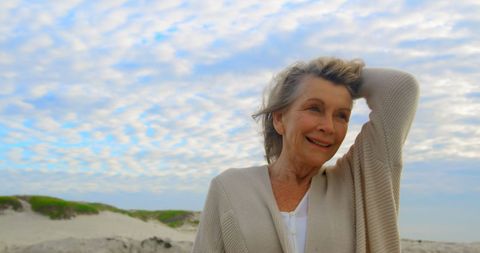 Senior Woman Smiling on Beach against Cloudy Sky