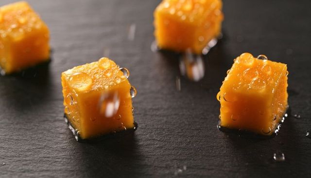 Glistening mango cubes with dew drops on dark slate closeup for food styling