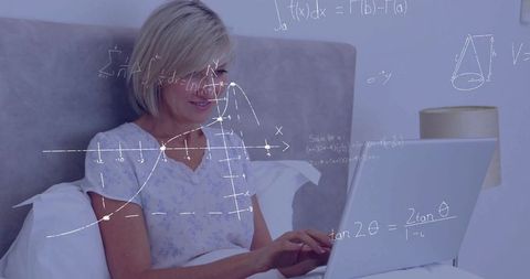 Mature woman learning online in cozy bedroom using laptop with floating math graphics