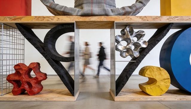 Displaying abstract porous sculptures on plywood shelves with visitors walking through
