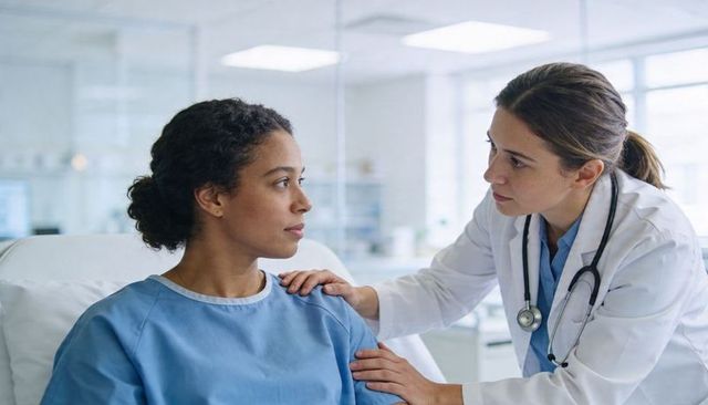 Physician comforting patient at bedside during clinical consultation, compassionate care