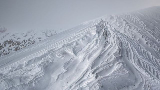 Wind-Sculpted Alpine Snow Ridge with Dramatic Cornices and Monochrome Winter Texture