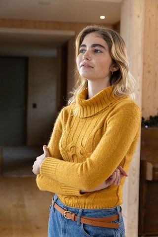 Thoughtful Woman in Mustard Sweater Leaning by Indoor Piano