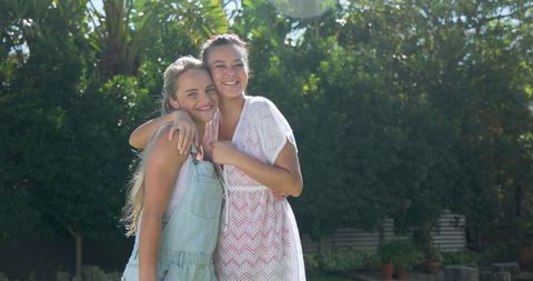 Joyful friendship: young women hugging in sunlit backyard