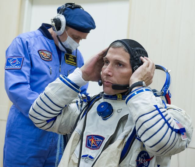 NASA engineer adjusting Sokol suit with assistance in Baikonur, Kazakhstan. Perfect for content about space missions, astronaut preparations, NASA's international collaborations, or human spaceflight history.