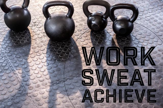 Motivational message 'Work Sweat Achieve' with kettlebells on gym floor. Ideal for fitness blogs, gym promotions, workout programs, and social media inspiration posts.