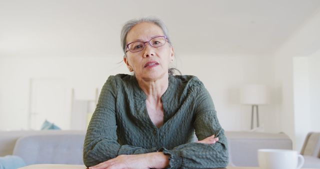 Senior Woman Sitting at Table with Thoughtful Expression at Home - Download Free Stock Images Pikwizard.com