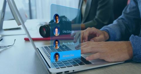 Typing on laptop with augmented reality contact list overlay in collaborative workspace