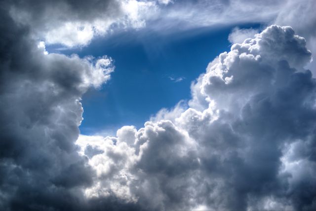 Dramatic storm clouds part, revealing blue sky above. Use for weather updates, nature blogs, inspirational quotes, atmospheric background, or dramatic scene setting in media projects.