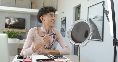 Young Man Applying Makeup at Home with Mirror and Light
