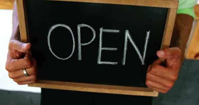 Hands of caucasian male business owner holding chalkboard open sign. Small business, business owner, work and lifestyle, unaltered.