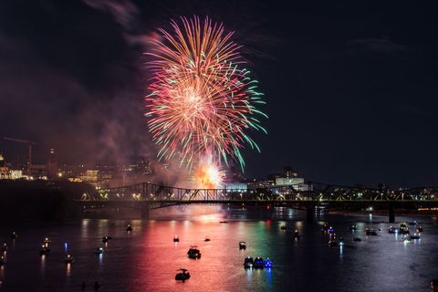 Colorful fireworks exploding over city river at night