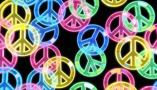 Glowing neon peace signs overlapping in colorful glassy rings on black backdrop
