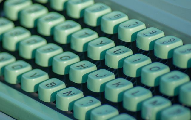 A close-up view of mint green typewriter keys, showcasing the tactile buttons and vintage aesthetics. Ideal for use in articles about writing, history of communication, or nostalgic themes.
