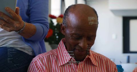 Senior man reading and smiling with companion holding tablet in cozy home interior