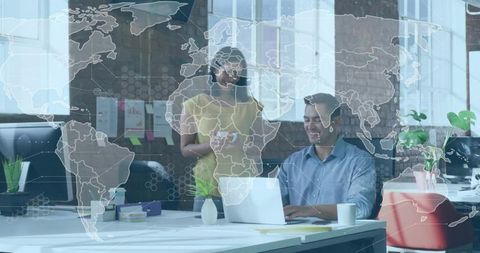 Collaborating team using laptop in modern coworking space with world map overlay