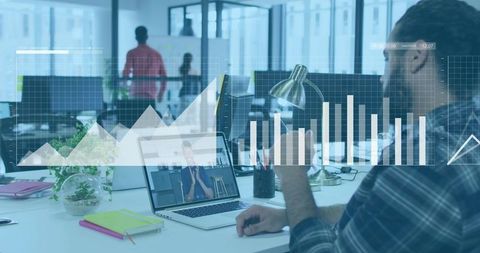 Man analyzing teleconference on laptop with digital data charts overlay in open-plan office team