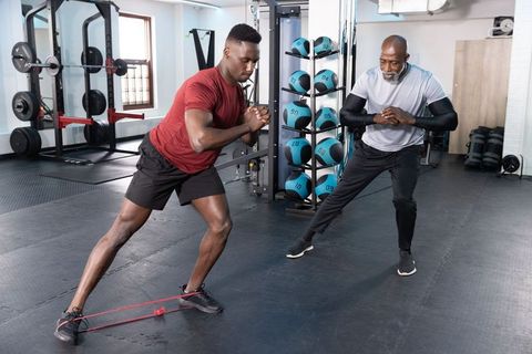 African american trainer coaching athlete performing lateral resistance band step workout