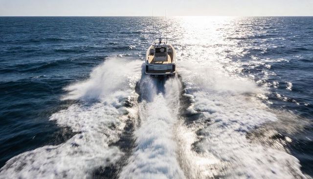 Luxury motor yacht cruising offshore, cutting twin foamy wake across sunlit ocean horizon