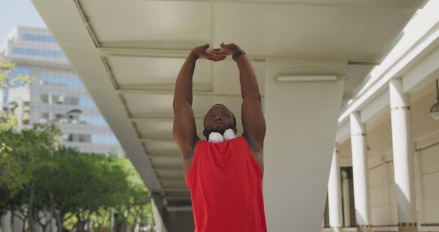 Young African American man stretching with headphones, outdoor urban setting - Download Free Stock Images Pikwizard.com