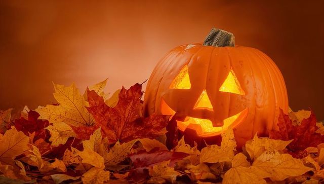 Glowing jack-o'-lantern amidst autumn leaves