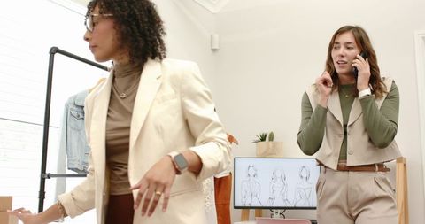 Female designers collaborating and styling garments in bright fashion studio