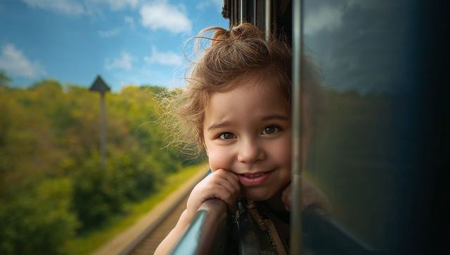Child smiling from train window during scenic journey
