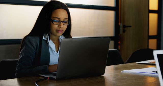 Young businesswoman using a laptop in an office environment. Ideal for illustrating concepts related to business, technology, professional life, and focused work ethic.