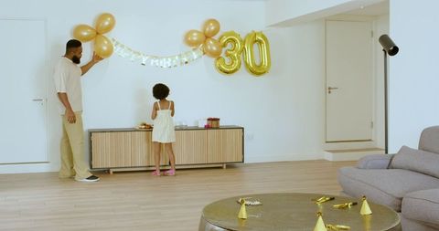 Father and daughter decorating living room for birthday party