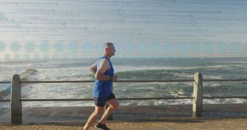 Senior Man Jogging Along Ocean Promenade Wearing Fitness Watch and Blue Running Gear