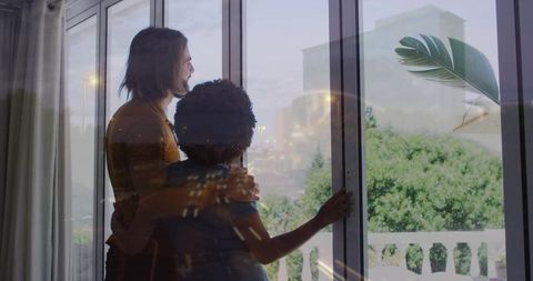 Couple Embracing and Gazing Through Sliding Glass Door with City Light Reflections
